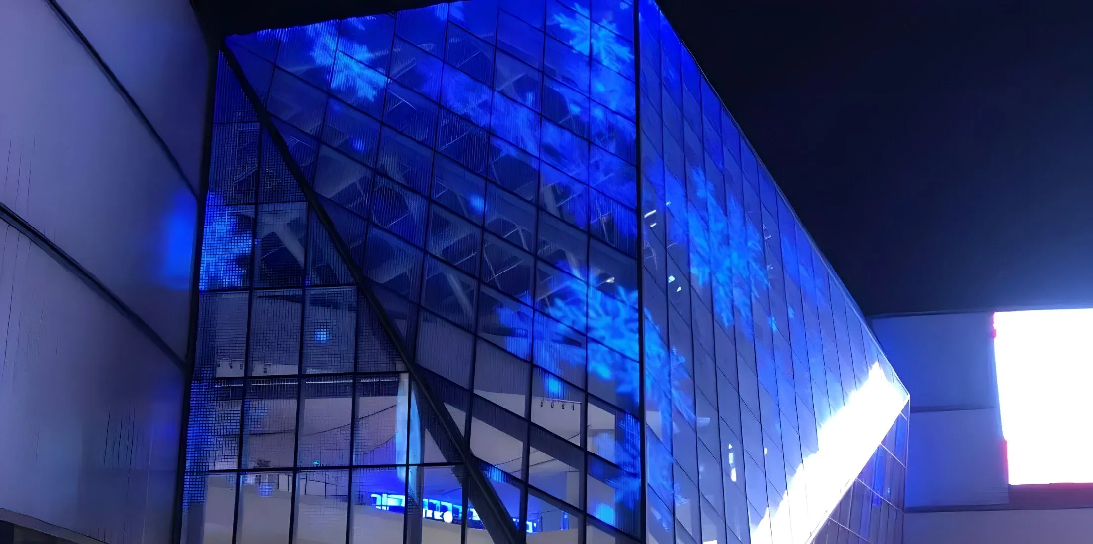 Large transparent LED glass curtain wall glowing blue at night